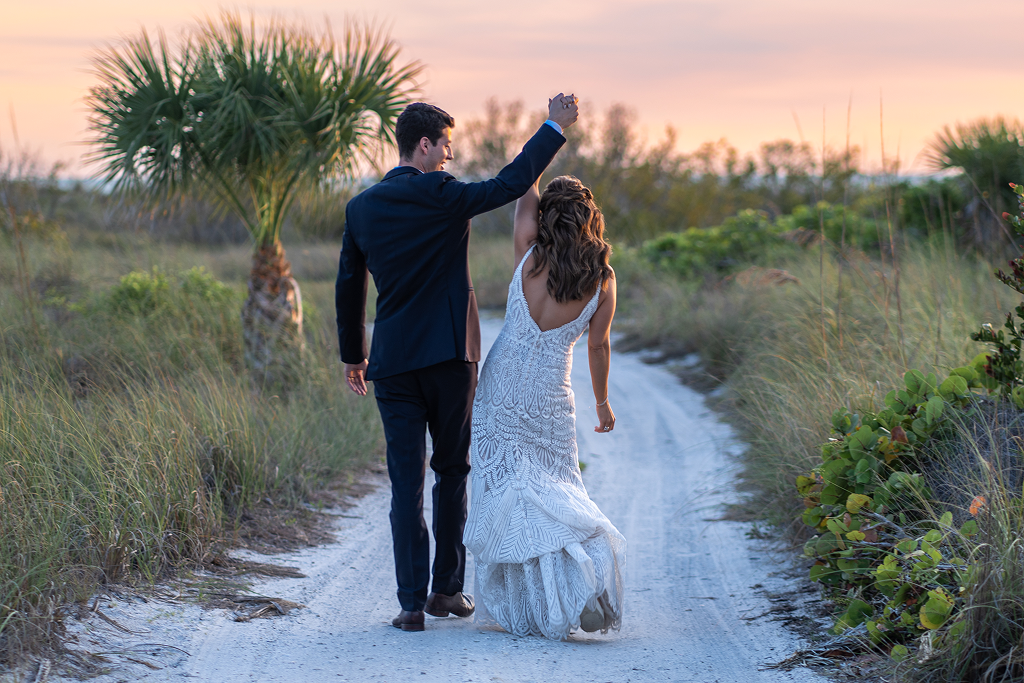 palm-island-resort-wedding-special: Sunset Wedding Portrait – Bride and groom holding hands on the beach at Palm Island Resort, with a vibrant sunset over the Gulf Coast
